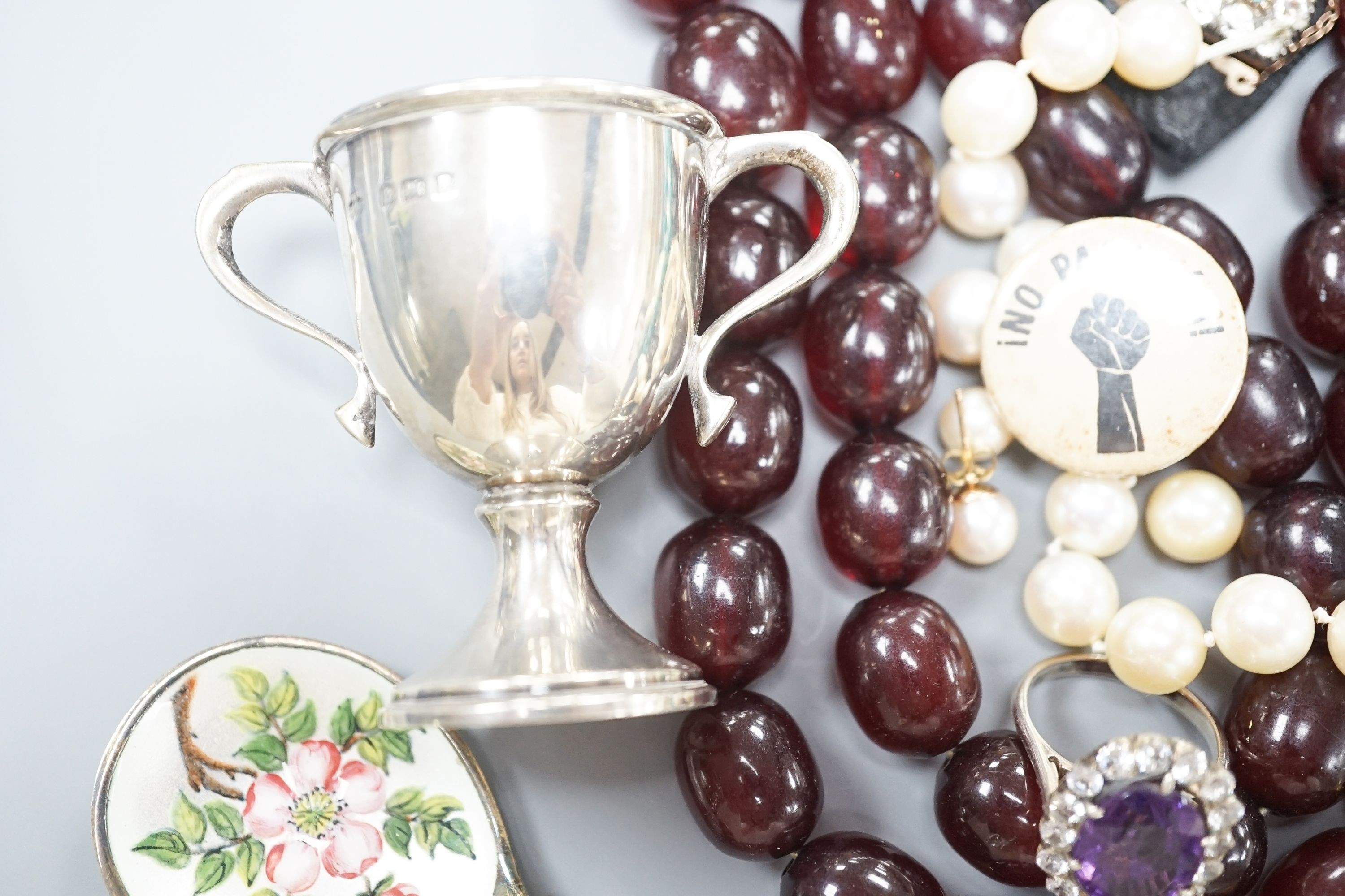 Assorted costume jewellery, etc. including small silver trophy cup, simulated amber necklace and git metal locket.